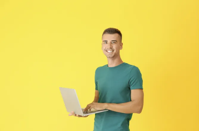 man with a laptop with yellow background writing a strong email