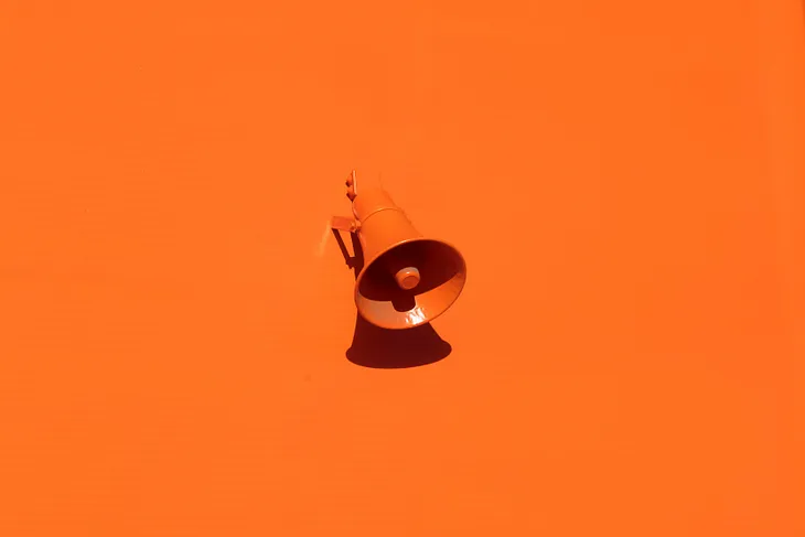 A photo of an orange bullhorn on an orange background