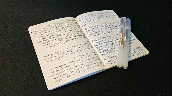 A notebook with a daily entry and two pens.