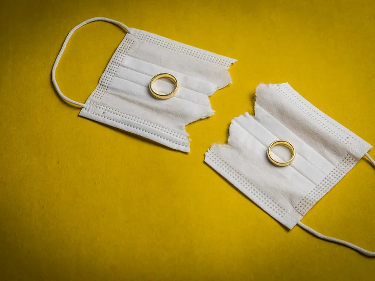 An image of two wedding rings on a torn-up face mask.