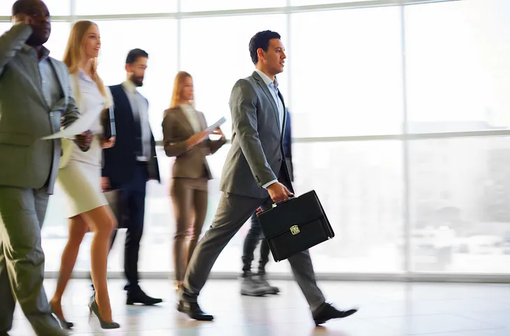 A man in a suit walking with people following him