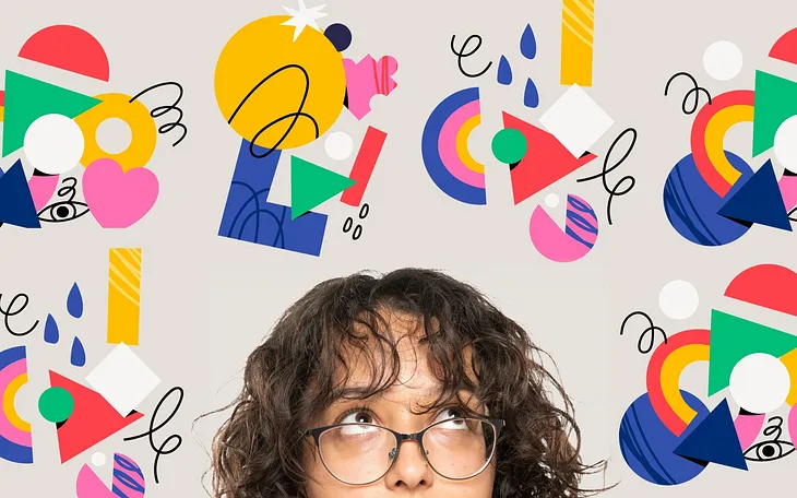 A woman with brown hair and glasses looking up at various brightly colored design elements swirling around her head.