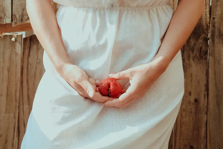 Woman holding a stawberry hip high suggestively