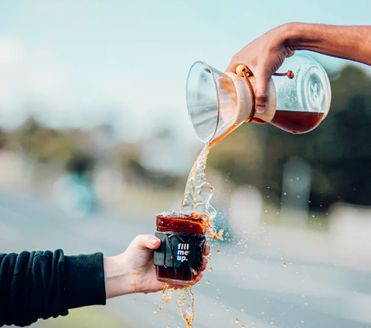 A photo of someone pouring a beverage into an overflowing cup labeled “Fill Me Up.”