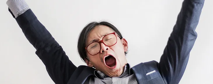 photo of yawning man with his hands up and eyes closed