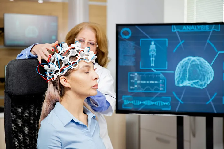 Doctor arranging scanning device on head of a female patient.