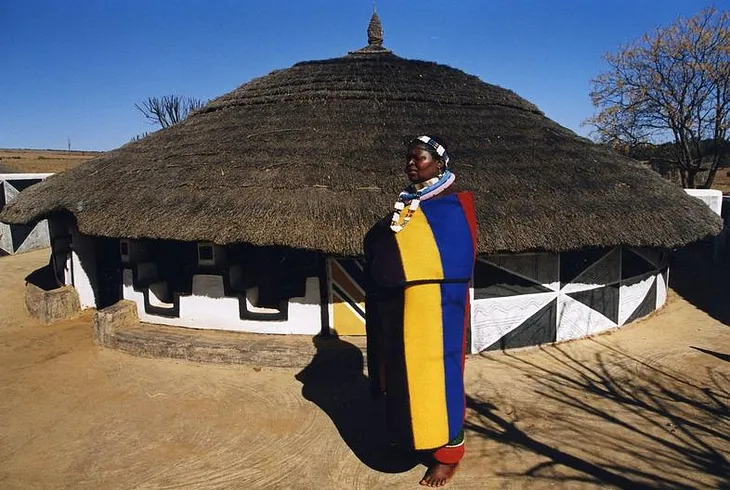Pedi woman infront of her Pedi decorated hut