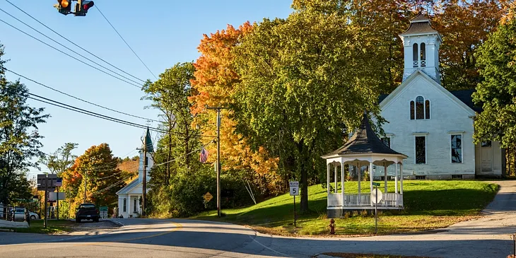 Beautiful New England town in the fall with leaves changing colors and two gorgeous church buildings with Steeples.