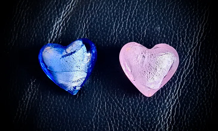 Two small glass hearts: one blue, and one pink