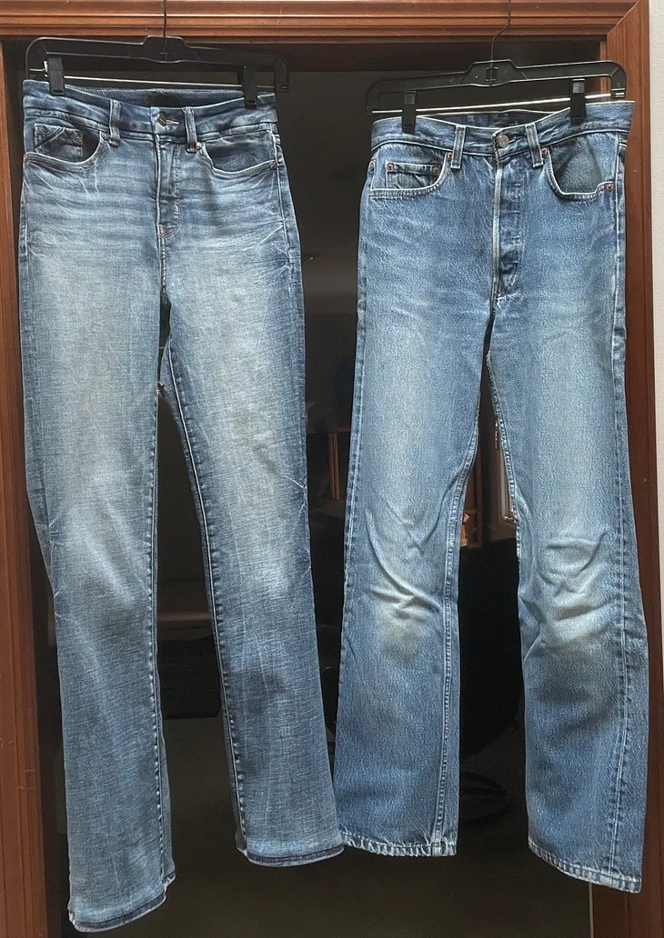 Two pairs of faded blue jeans hang from a door frame