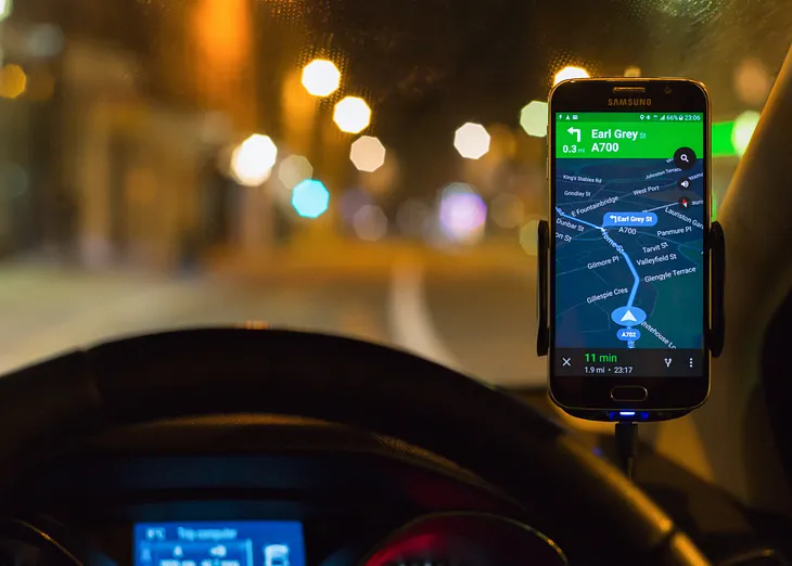 Google Maps on a phone mounted above a car dashboard.