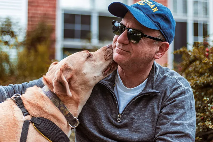 Dog licking happy man on the face