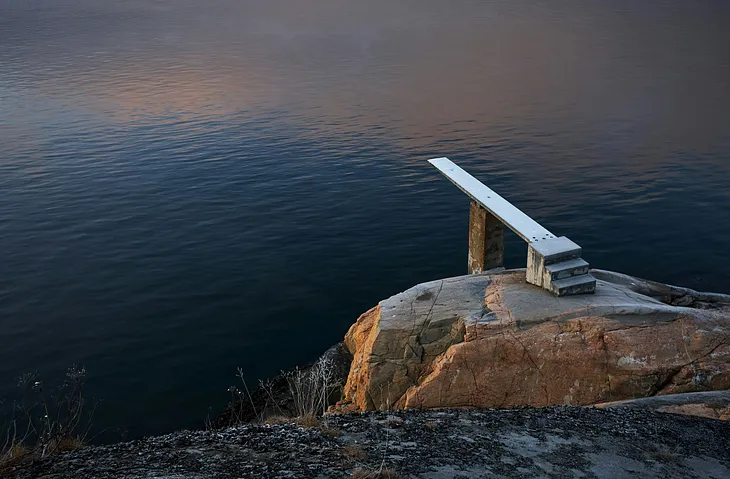 Photo of a diving board next to a natural body of water.