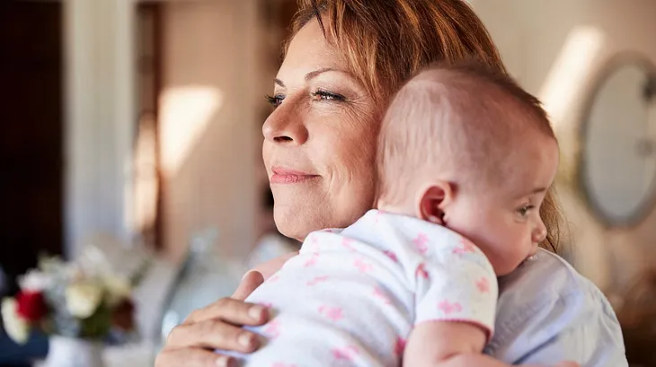 A middle aged woman holds a baby.