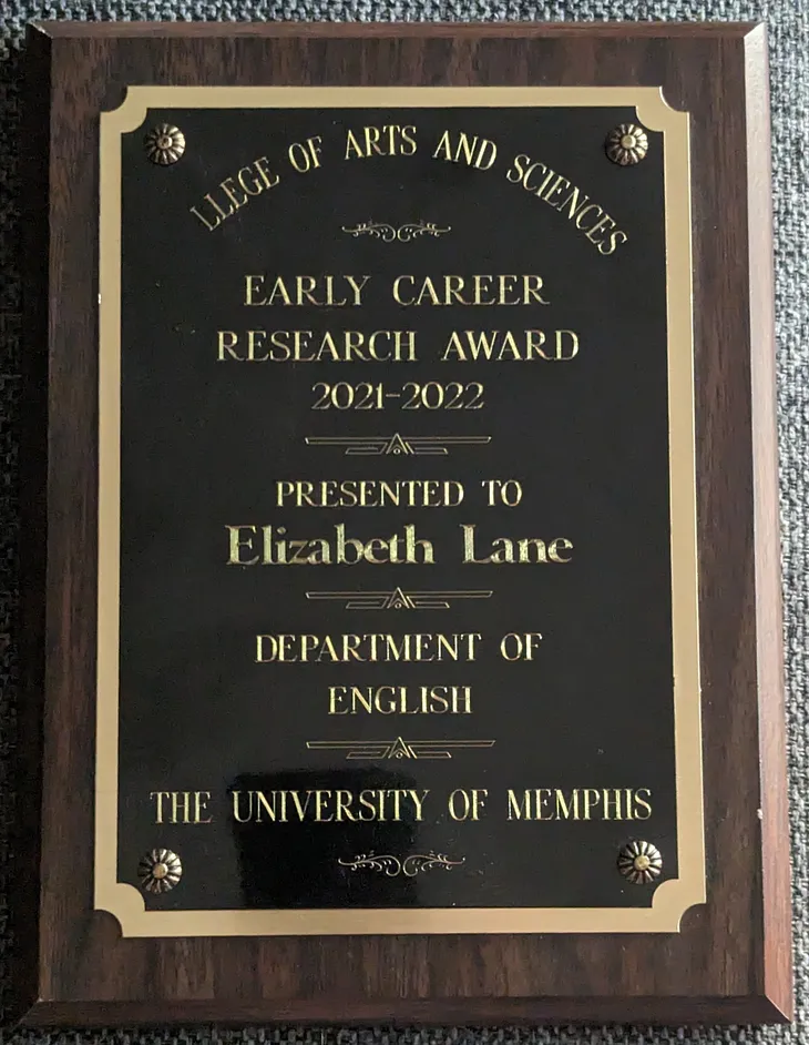 An image of a wooden plaque with a metal plate, engraved with the words Early Career Research Award