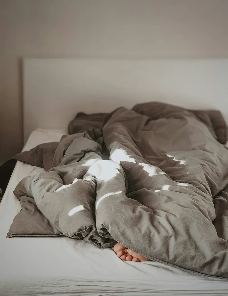 A person sleeping under a blanket and a foot’s toes popping out. Relatable stories, daily lifestyle, sleeping habits, waking up, funny.