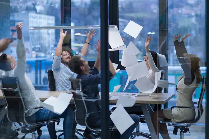 group of business professionals at work in a conference room throwing documents in the air