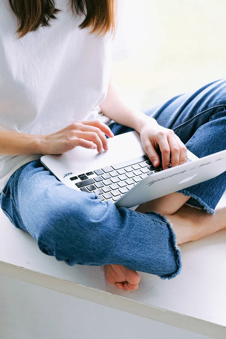 Woman sitting with an open Apple laptop in her lap.