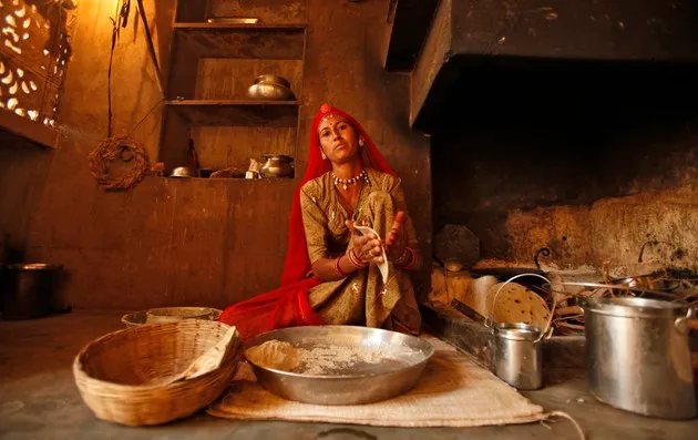 An Indian woman makes bread. Her shelves are at a low height, which is common in floor-sitting cultures.