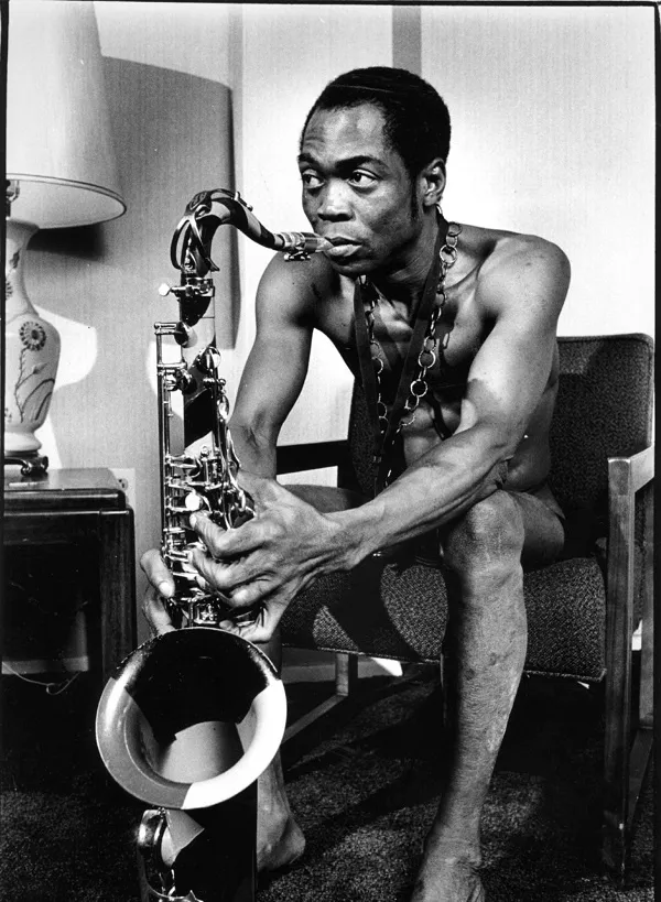 A photo of Fela Kuti sitting, holding a saxophone