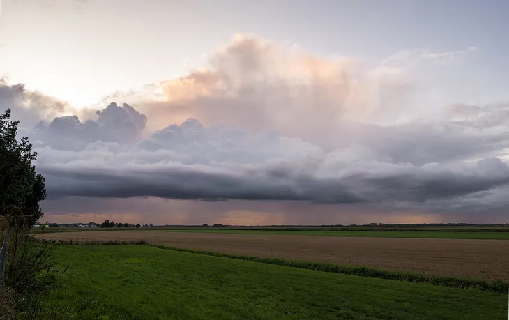 Panoramic photo of approaching storm clouds over farm fields.