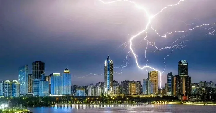 Haikou Hainan Cityscape with large lightning bolt in background with grey and purple skies in middle of the Typhoon by Suzanne Marie