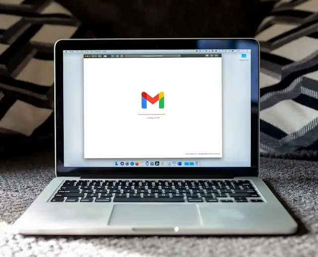 A MacBook laptop sitting open on a desk with a Gmail browser window on the screen