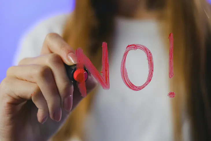 Woman writing NO! on a mirror in lipstick