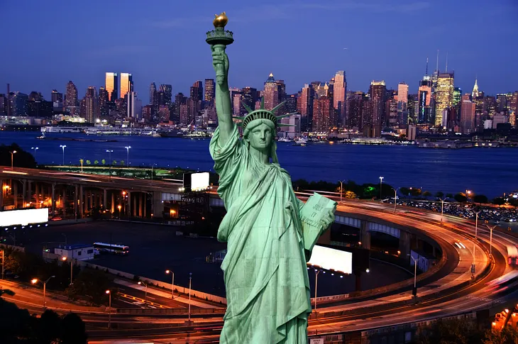 night image of New York, with Statue of Liberty in foreground.