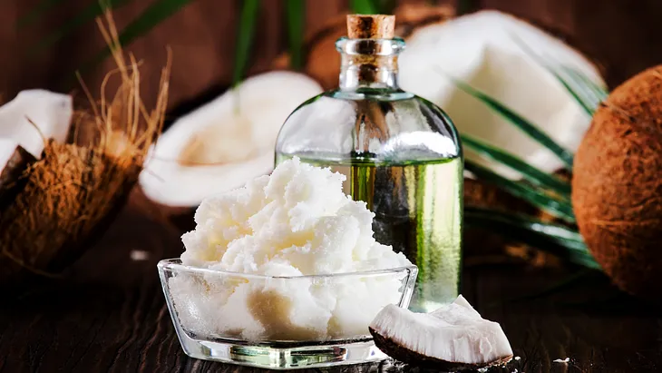 An image of MCT Oil in a jar with some coconuts beside it.