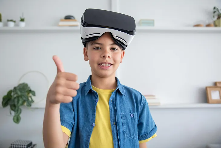 A Boy Wearing Virtual Reality Goggles with a thumbs up sign.