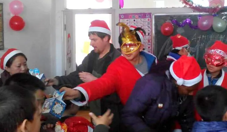 Evan wearing a Santa hat and passing out presents to students.