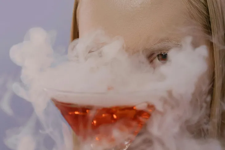 Woman’s face behind a foaming glass of red liquid