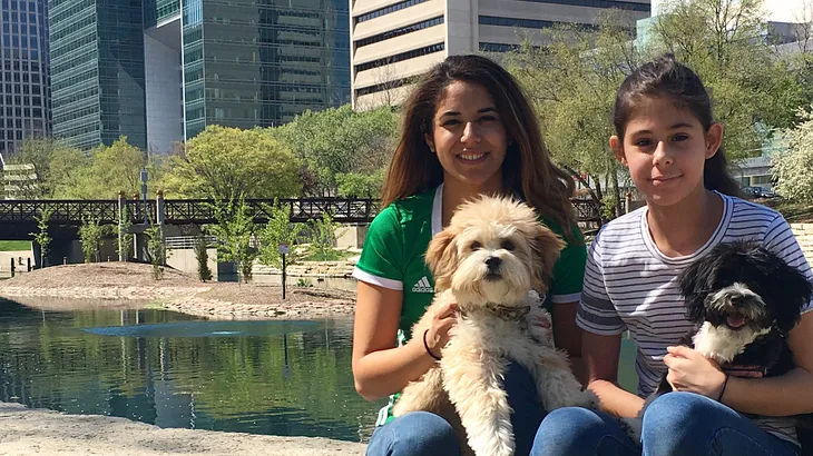 Trisha and her sister Eliana with their dogs, Leo and Luna at a park