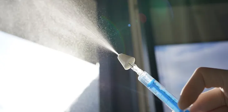 A hypodermic needle spraying out a substance