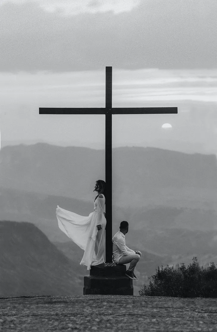 Man and Woman Pose On a Cross Monument