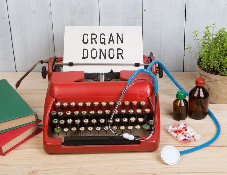 A red typewriter prints a page that reads “ORGAN DONOR.”
