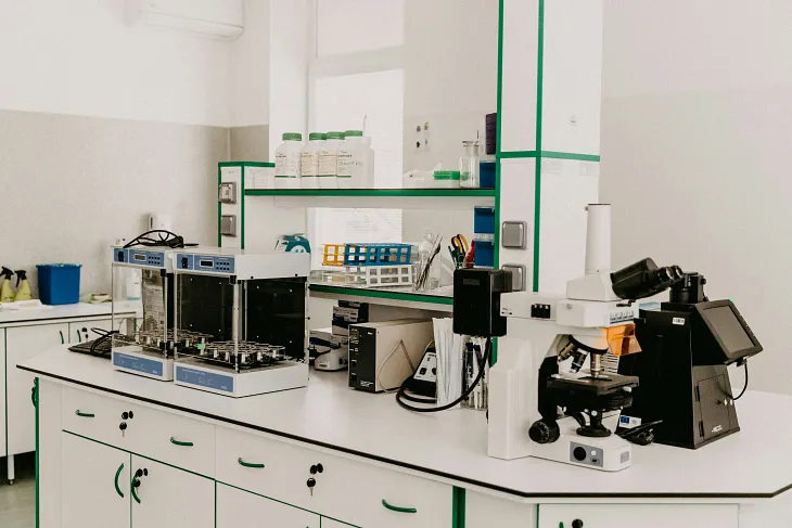 Image of a clean and well-organized laboratory with various equipment including microscopes, machines, and bottles on the counters and shelves.