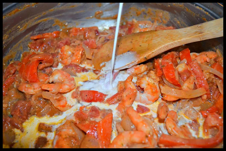 Adding cream to a pot while making Busy Day Pasta with Creamy Shrimp Sauce