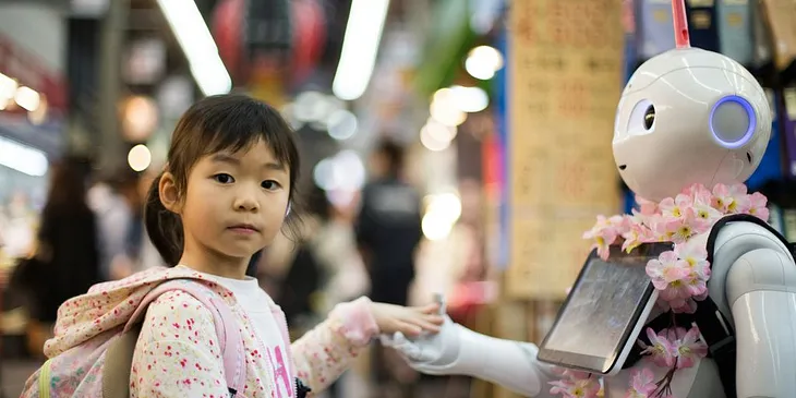Young girl interacting with a humanoid robot adorned with pink flowers in a busy market setting.