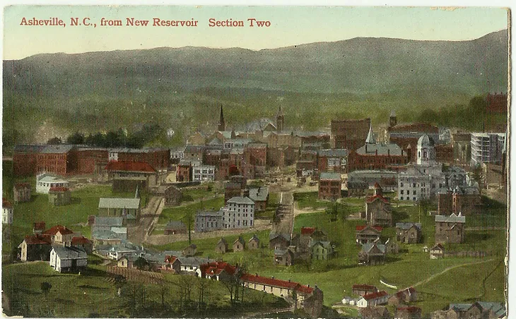 A painted postcard with a view of Asheville, NC from New Reservoir. It appears as a small town with red brick and white wood buildings against a backdrop of mountains.