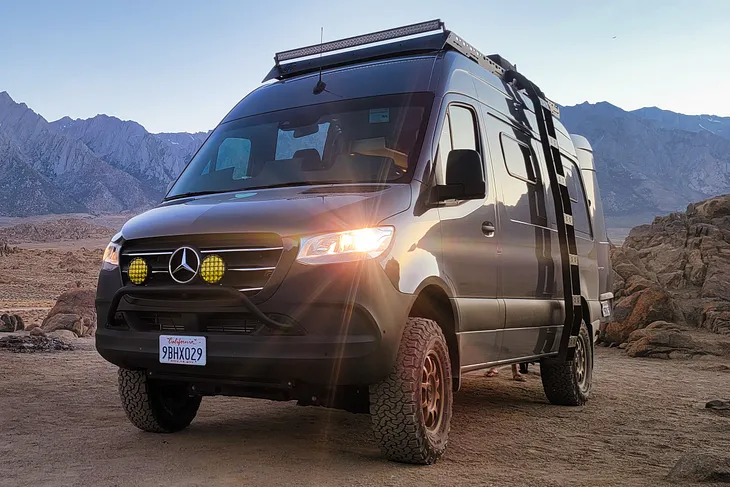 Mercedes Sprinter camper 4x4 in grey with front foglights on with mountains in the background