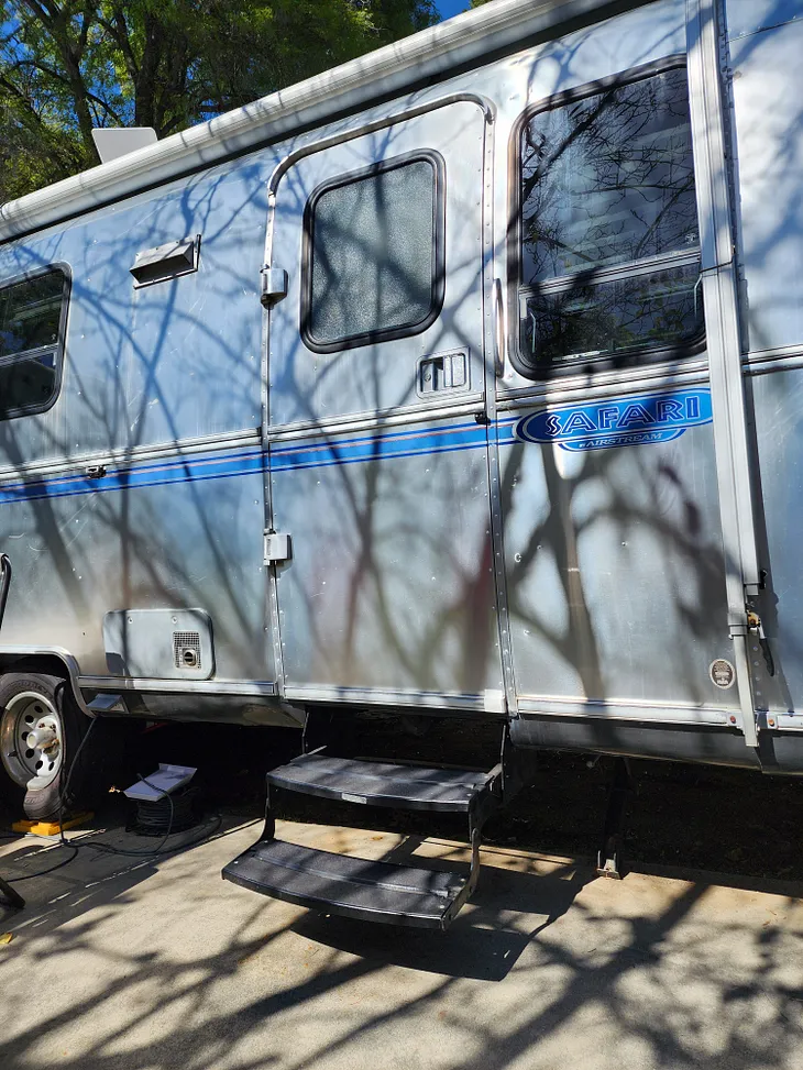 Picture of the side of an Airstream trailer with the steps deployed, but the door closed.