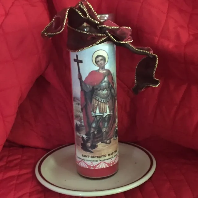 A photo of a tall votive candle portraying a Roman Centurion holding a cross in one hand and a palm frond in the other. Saint Expedite.