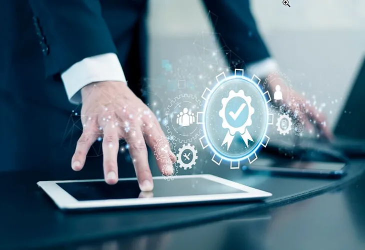 An illustration with a man’s hand touching an iPad and symbols indicating gears floating in the air above it.