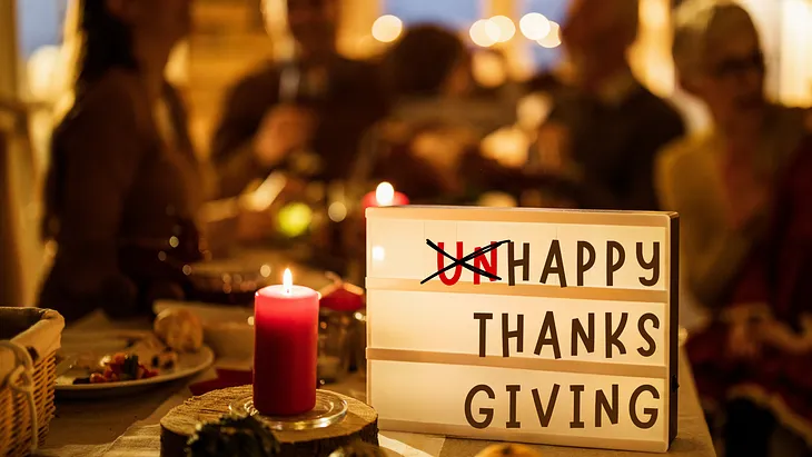 Thanksgiving dinner table with candle and sign saying happy thanksgiving