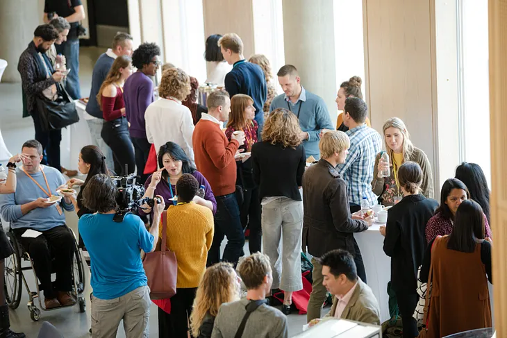 A group of people meeting at a conference and mingling together in conversation