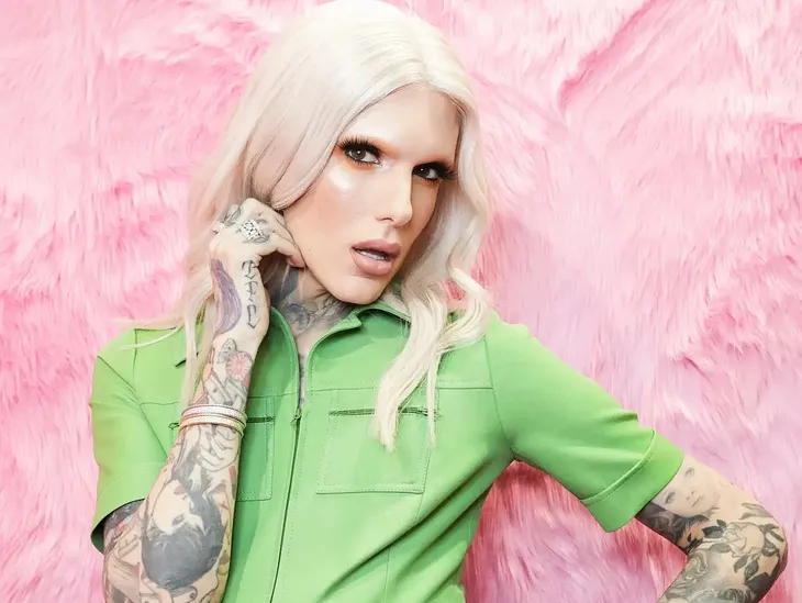 A photo of Jeffree Star with a blonde wig and his tattoos showing