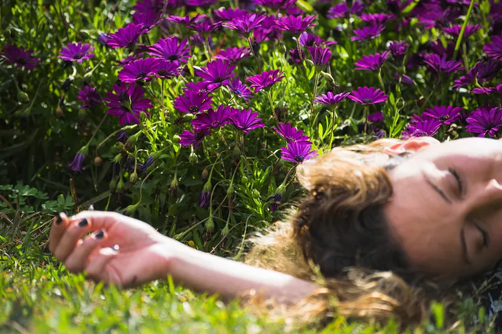Woman lying besides flowers