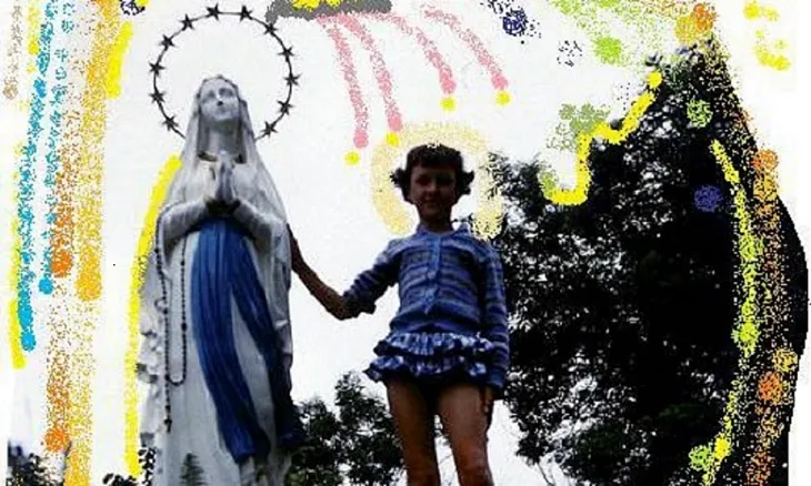 young girl holds hand of Mother Mary statue.